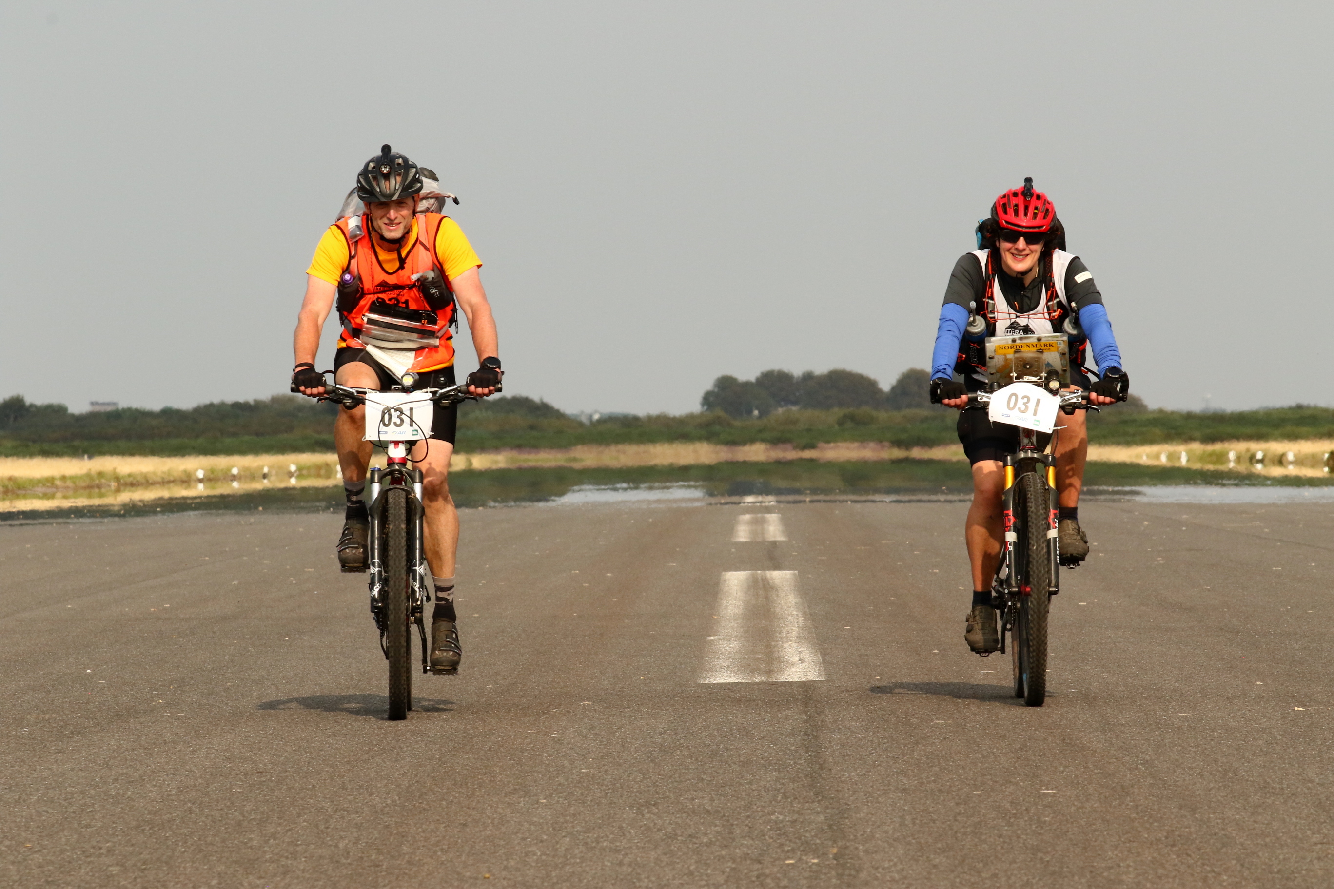 We are riding down a runway, Dave on the left, me on the right. There is a white dashed line between us, which disappears behind us in a shimmering heat haze.